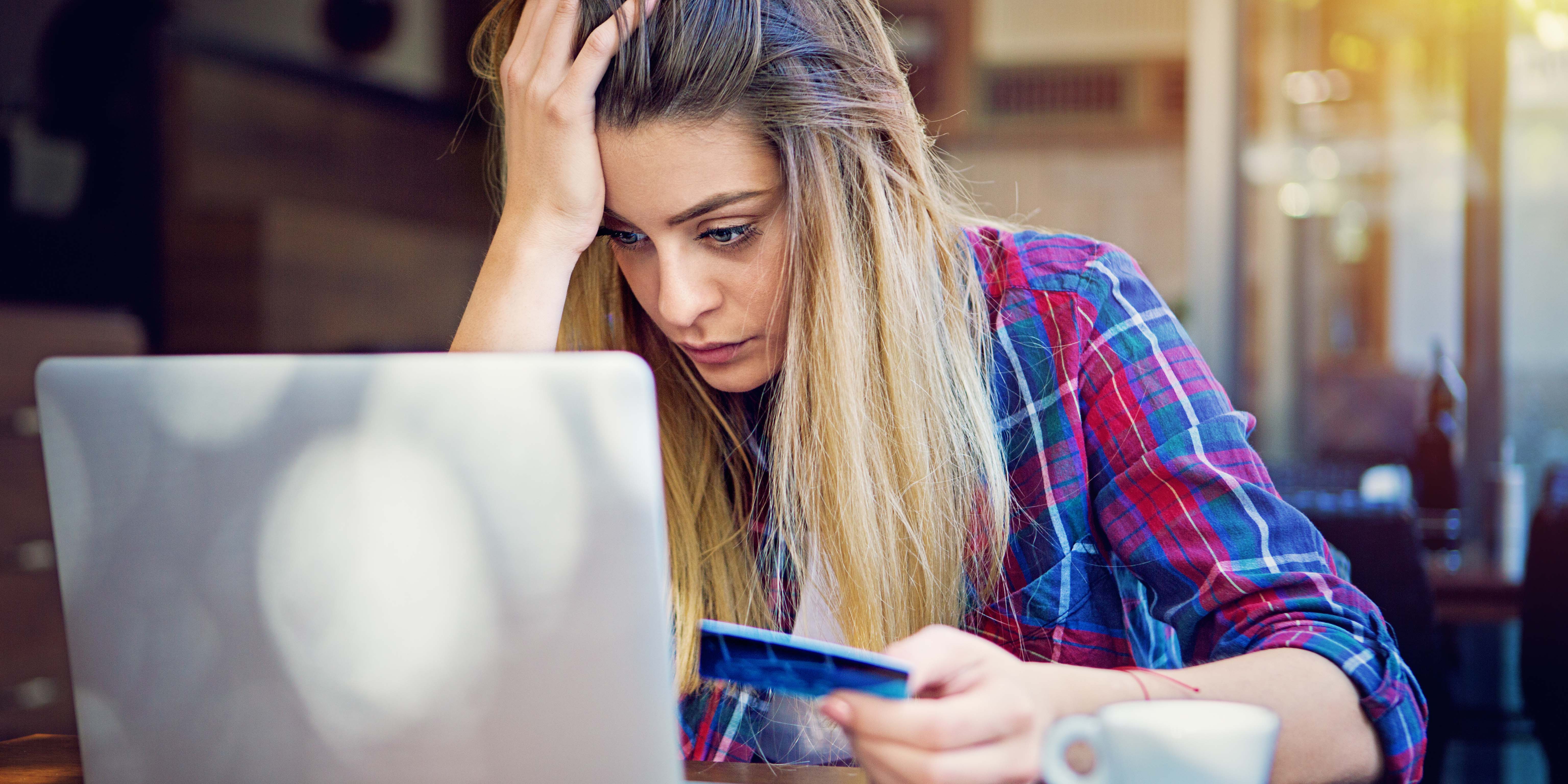 Frustrated woman stares at laptop holding credit card